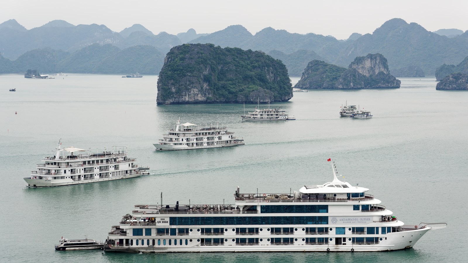 Cruise boats on the emerald water of Ha Long Bay, Vietnam, with forested limestone islands behind