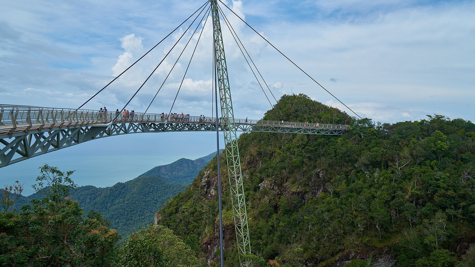 The curved Langkawi Sky Bridge on its single pylon above the rainforest in Langkawi, Malaysia, with the sea in the distance