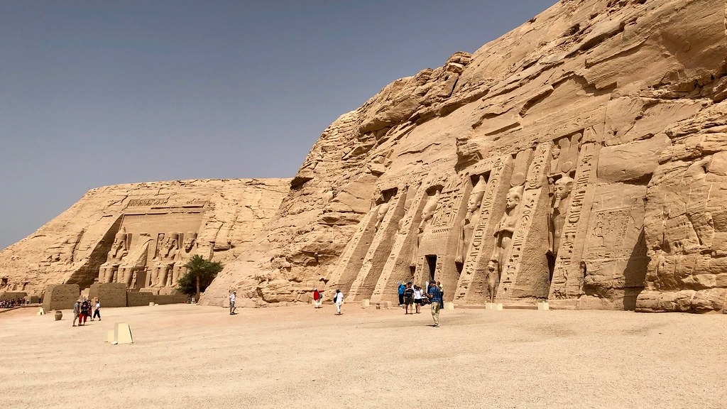 The Great Temple of Abu Simbel with its colossal statues and the smaller Temple of Nefertari behind it, with visitors for scale.