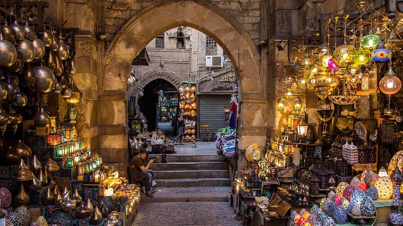Lantern and souvenir stalls under a stone archway in Khan el-Khalili bazaar, Cairo.