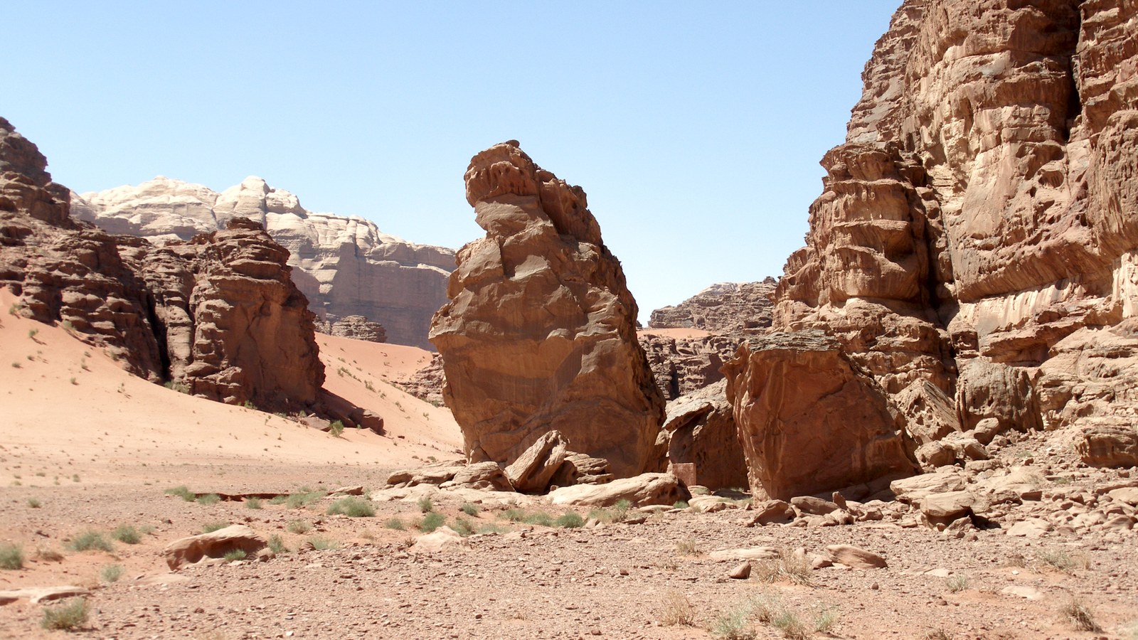 Red sand and weathered sandstone towers and jebels in the Wadi Rum desert, Jordan, under a clear blue sky