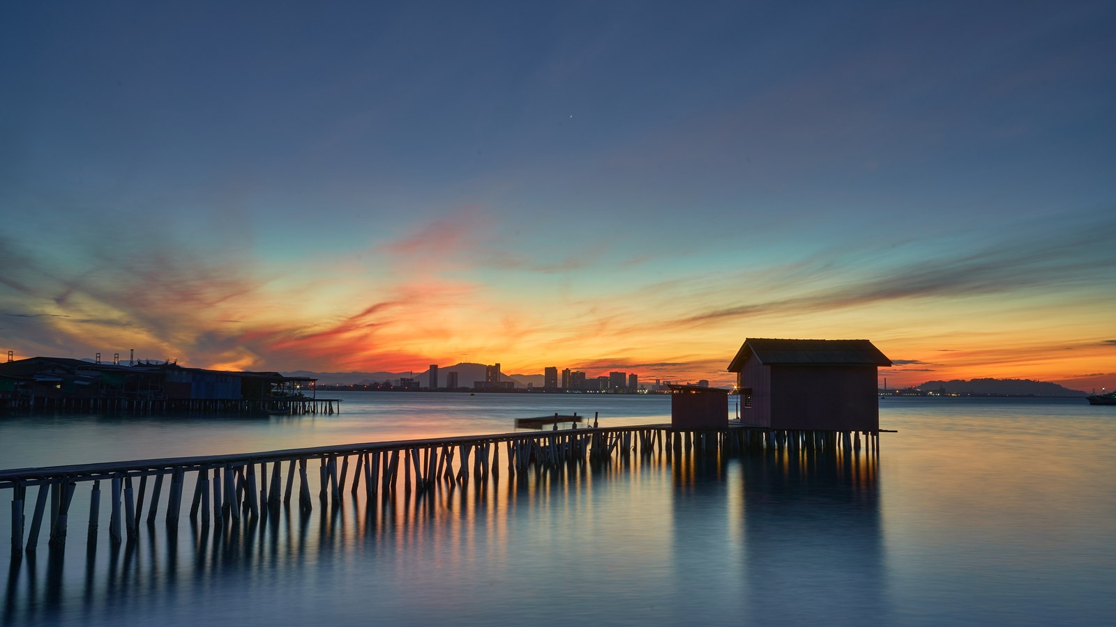 A clan jetty stilt house at dawn over calm water in George Town, Penang