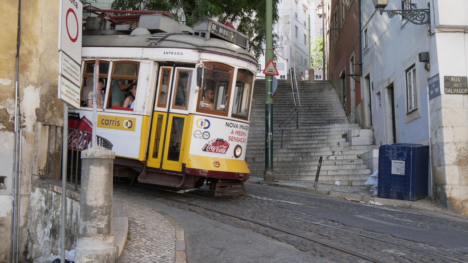 Yellow tram 28 climbing a narrow cobbled street in Alfama, Lisbon