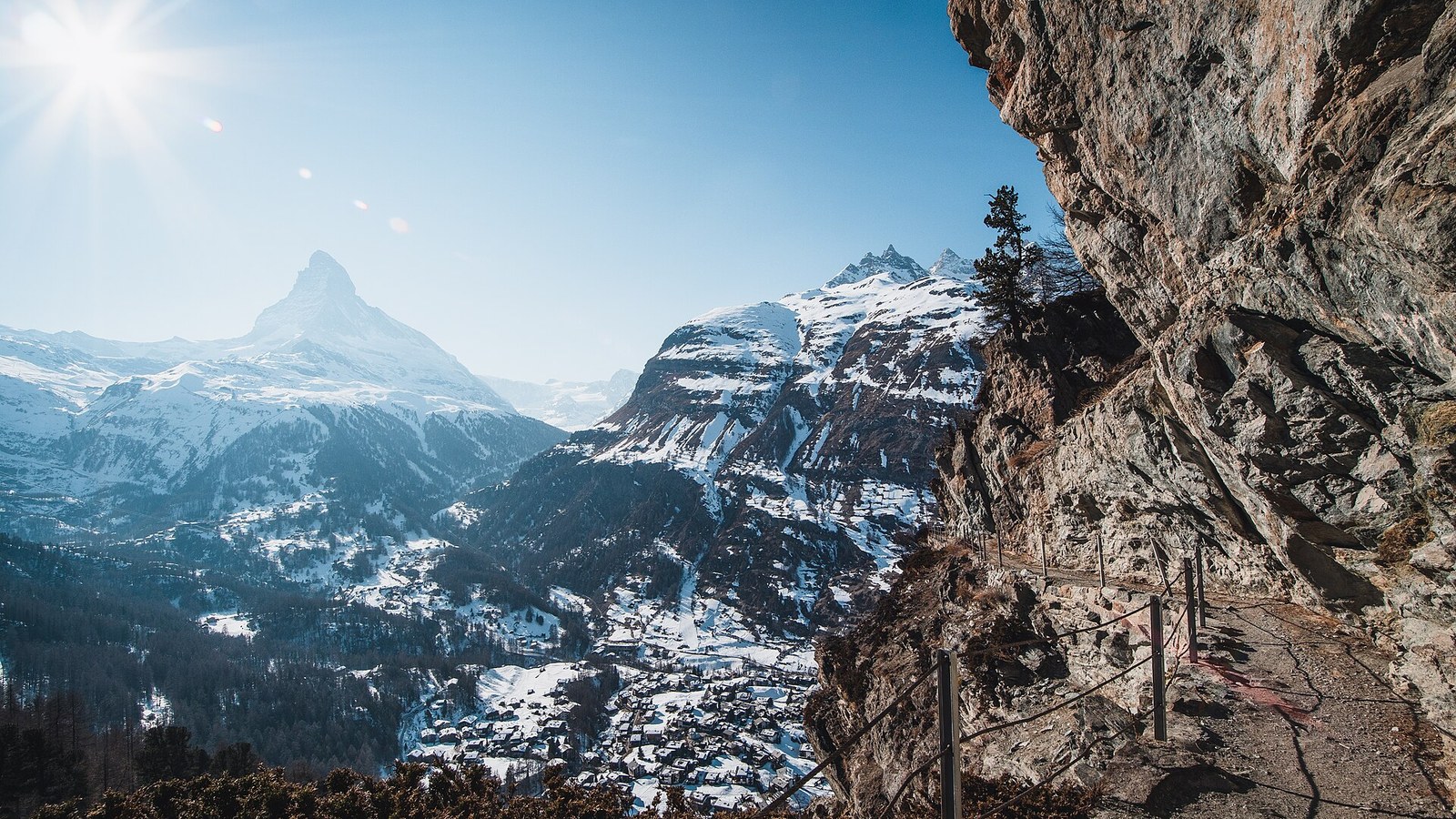 Snow-covered Zermatt village in winter below the Matterhorn, seen from a cliff path in the Swiss Alps